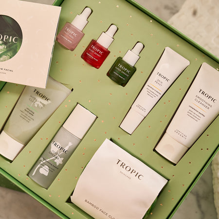 The Advanced Glow Facial Active Skincare Collection from Tropic, featuring a green gift box filled with cleansers, serums, creams, and a bamboo face cloth for a complete skincare routine.